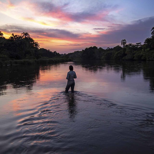 Viajera contemplando el atardecer sobre el río en Lango Baï, Odzala-Kokoua (República del Congo).